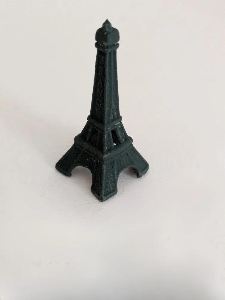 La petite Tour Eiffel en métal, posée sur un plan clair