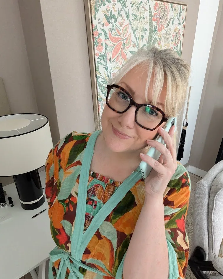 Aurélie au téléphone, souriante, dans un intérieur fleuri